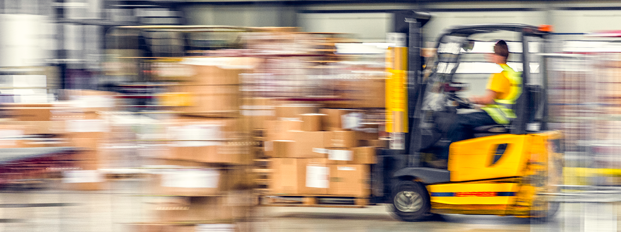 Blurred motion of forklift in warehouse.