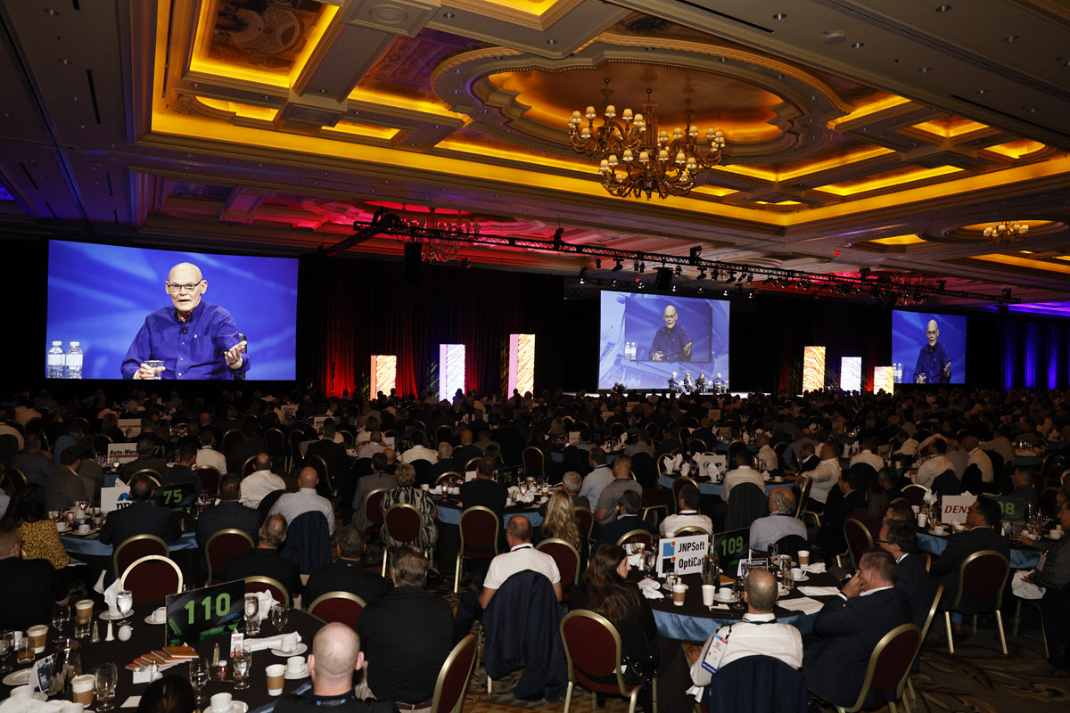 A packed general session ballroom with the speaker on large screens